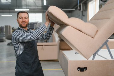 Bir mobilya fabrikasında kanepe monte eden bir zanaatkar, titiz kaliteyi ve ustalığı her detayına kadar vurguluyor.