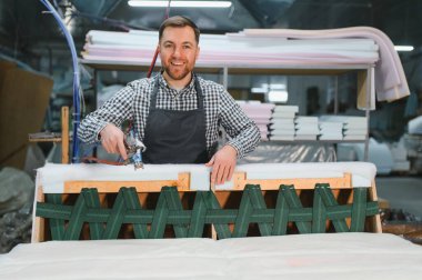 Mobilya fabrikasında çalışan bir işçi, bir kanepe montajı bir cnc makine kullanarak, sanatçılık ve modern üretim teknikleri sergileniyor.