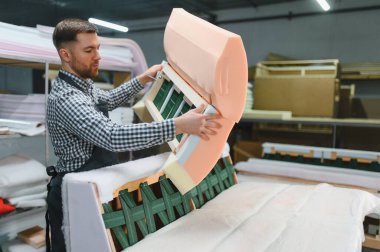 Marangoz mobilya fabrikasında kanepe monte ediyor, el yapımı mobilyaların karmaşık üretim sürecini gözler önüne seriyor.