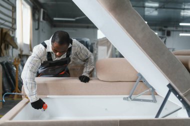 Afrikalı Amerikalı işçiler bir mobilya fabrikasında kanepeyi ustalıkla birleştiriyor, alet ve makineleri kusursuz işçilik için kullanıyor.