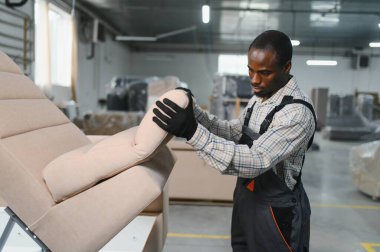 Marangoz, işlek bir mobilya fabrikasında şık bir kanepe kuruyor. Yetenekli işçilik ve mobilya üretiminde kalite sergiliyor.