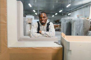 Mobilya fabrikasında gülümseyen Afrikalı bir Amerikan işçisinin portresi.