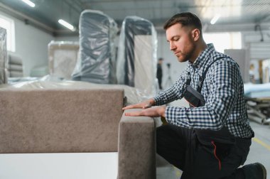 Marangoz bir mobilya fabrikasında kanepe monte ederek yüksek kaliteli döşenmiş mobilyaların karmaşık üretim sürecini sergiliyor.