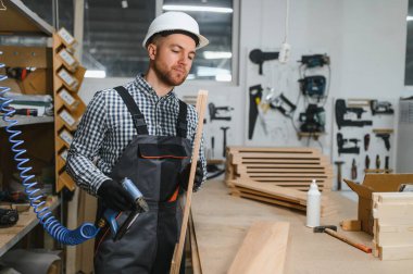 Mobilya fabrikasında çalışan bir işçi kesin odun kesme makinesi kullanıyor. Sanatçılık ve modern üretim tekniklerine odaklan.