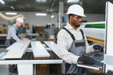 İki fabrika işçisi bir mobilya fabrikasında kanepe üretimi için odun kesmek için bir cnc makinesi kullanıyorlar.