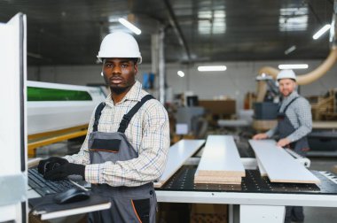 Marangozlar bir mobilya fabrikasında ahşap tahtalar keserek ahşap bir makine ile çalışıyorlar.
