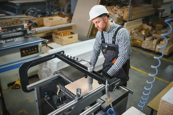 Marangoz, modern bir fabrika ortamında mobilya parçaları üreten bir Cnc makinesi kullanıyor.