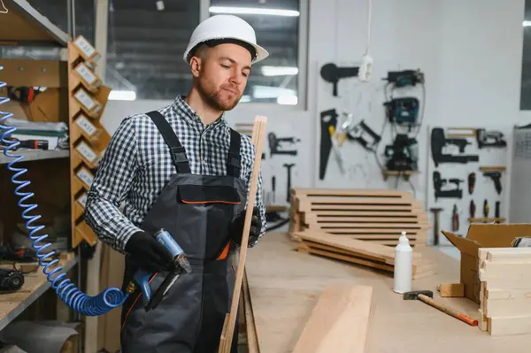 Mobilya fabrikasında çalışan bir işçi kesin odun kesme makinesi kullanıyor. Sanatçılık ve modern üretim tekniklerine odaklan.