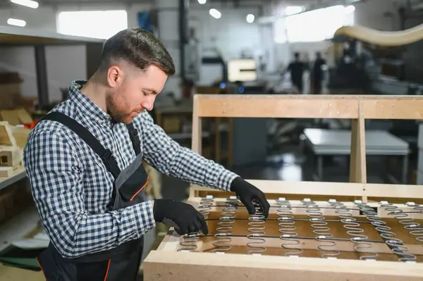 Marangoz mobilya fabrikasında yayları olan kanepe çerçevesi montajı, sanatçılık ve üretim süreci