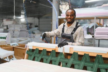 Marangoz, hareketli bir mobilya fabrikasında kanepe imalatında çalışıyor. Kaliteli ev mobilyaları için ustalıkla parçaları birleştiriyor.