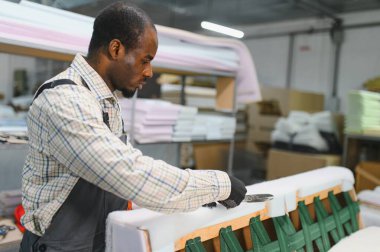 Marangoz, mobilya fabrikasındaki bir koltukta ustalıkla çalışıyor. Döşeme ve tasarım için makaslarla kumaşı ustalıkla kesiyor.