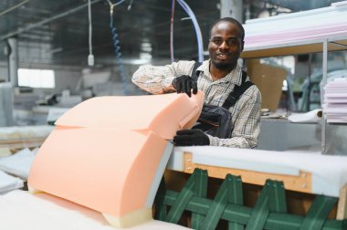 Marangoz yoğun bir mobilya fabrikasında kanepe monte ediyor. Kaliteli mobilyalar yapmak için köpük ve ahşap ustalıkla çalışıyor.