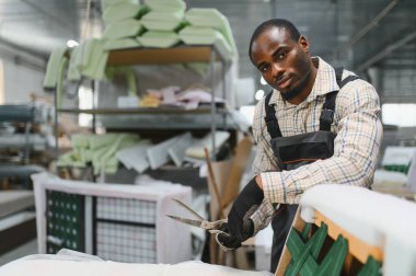 Mobilya fabrikasında bir koltukta çalışan yetenekli bir zanaatkar mobilya üretim sürecini gösteriyor.