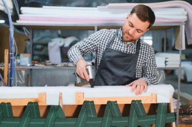 Marangoz, hareketli bir mobilya fabrikasında kanepe döşeyip, marifetli işçilik sergilerken pnömatik zımba tabancası kullanıyordu.