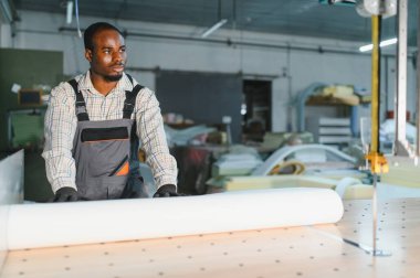 Marangoz bir mobilya fabrikasında beyaz döşeme kumaşı rulosu hazırlıyor.