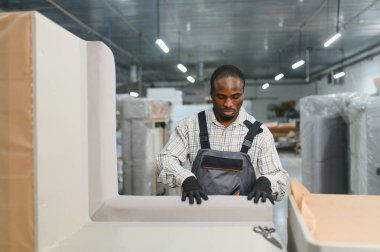 Marangoz, hareketli bir mobilya fabrikasında kanepeyi ustalıkla döşeyip tasarımını ve kalitesini arttırmak için kumaşı titizlikle uyguluyor.