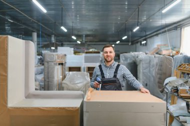 Marangoz elinde pnömatik çivi tabancası mobilya fabrikası deposunda kanepe montajı, döşenmiş mobilya üretim süreci