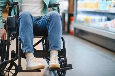 Tekerlekli sandalyeyle market alışverişi, ulaşılabilir alışveriş ve maluliyet konsepti yapan bir adam.