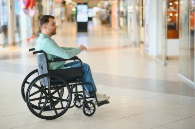 Tekerlekli sandalyedeki müşteri, alışveriş merkezinin erişilebilirliğinin keyfini çıkarıyor, engelliler için kapsayıcılığı ve bağımsız hareket kabiliyetini destekliyor