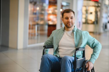 Tekerlekli sandalye kullanan gülümseyen bir adamın portresi, alışveriş merkezinde eğlenen, ulaşılabilirlik ve kapsayıcılık sergileyen...