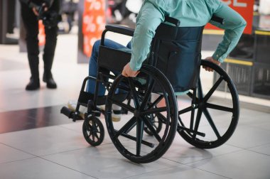 Alışveriş merkezinde tekerlekli sandalye kullanan kişi, engelliler için ulaşılabilirlik ve hareketliliği sembolize ediyor