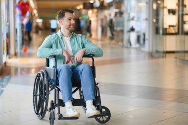 Tekerlekli sandalyedeki bir alışveriş merkezinde gezinen engelli biri. Erişilebilirlik ve kapsayıcılığı gösteriyor.