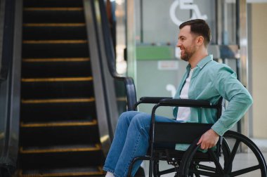 Tekerlekli sandalyede yürüyen merdiven gözlemleyen bir adam, kamu alanlarında dolaşım bozuklukları ve ulaşılabilir altyapı ihtiyacı olan bireylerin karşılaştığı zorlukları gösteriyor.
