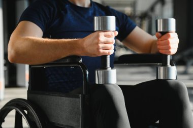 Spor salonundaki rehabilitasyon sırasında dambıl kaldıran kararlı erkek sporcu fiziksel zorlukların üstesinden gelmek için güç ve direnç gösteriyor.