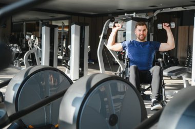 Tekerlekli sandalyedeki adam ağırlık kaldırıyor, spor yapıyor, dayanıklılık gösteriyor ve rehabilitasyon ve adaptif sporlarla sağlıklı yaşam tarzını sürdürüyor.