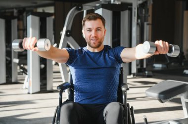 Modern spor salonunda rehabilitasyon eğitimi sırasında direnç ve güç gösteren engelli bir adam.