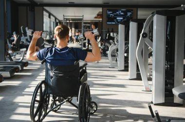 Spor salonundaki rehabilitasyon sırasında halterleri kaldıran hasta, dayanıklılık ve dayanıklılığı kucaklarken güç eğitimi ve iyileşmeye odaklanıyor.