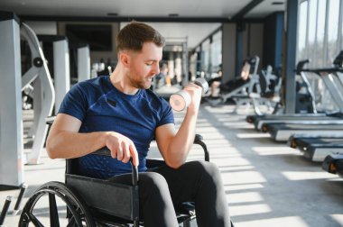 Spor salonunda dambıllarla egzersiz yapan, rehabilitasyon terapisi sırasında azim ve güç gösteren biri.
