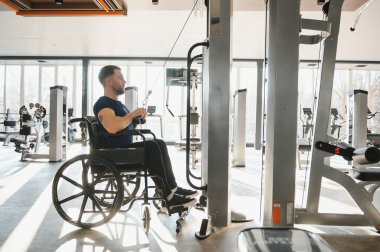 Modern bir spor salonunda rehabilitasyon ve fizik tedavi için özel ekipman kullanan hasta, ulaşılabilir fitness ve iyileşmeyi teşvik ediyor.