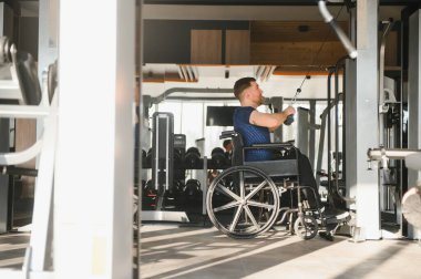 Spor salonunda halat ağırlığıyla egzersiz yapan, rehabilitasyon sırasında azim ve güç gösteren biri.