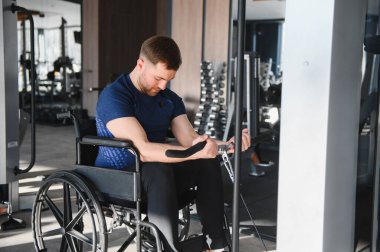Modern spor salonunda kablo makinesiyle egzersiz yapan, rehabilitasyon tedavisi gören, kararlılık ve güç gösteren biri.
