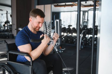 Spor salonunda kablo makinesiyle kol egzersizi yapan, rehabilitasyon eğitimine dahil olma ve kararlılık gösteren biri.