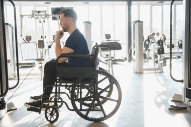 Hasta, fiziksel kısıtlamalara rağmen kararlılık ve güç gösteren kablo ağırlıklarıyla rehabilitasyon egzersizleri yapıyor.