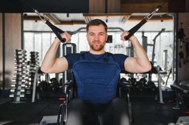 Modern spor salonunda ağırlık egzersizi yapan güçlü sporcu rehabilitasyon tedavisi görüyor ve spora dahil edilmesini teşvik ediyor.