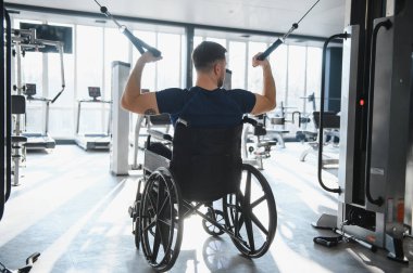 Kablo sıra makinesi kullanan, vücut gücünü arttıran, dayanıklılık gösteren ve fiziksel kısıtlamalara rağmen fitness hedeflerine ulaşan bir adam.