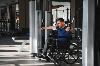 Engelli bir sporcu modern bir spor salonunda kablo ağırlıklarıyla egzersiz yapıyor rehabilitasyon eğitiminde güç ve direnç gösteriyor.