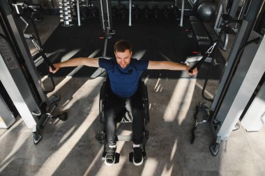 Gülümseyen adam rehabilitasyon ve fitness eğitimi için erişilebilir spor aletleri kullanıyor, engelliler için kapsayıcılığı ve aktif yaşam tarzını teşvik ediyor