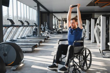 Spor salonunda rehabilitasyon sırasında ağırlık kaldıran engelli bir adam azim ve güç gösteriyor.