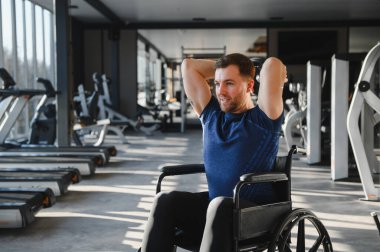 Spor salonunda halterli halterle egzersiz yapan engelli bir adam rehabilitasyona ve forma bağlılığını gösteriyor.