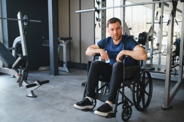 Engelli erkek sporcu erişilebilir spor salonundaki rehabilitasyon egzersizleri sırasında ara veriyor.