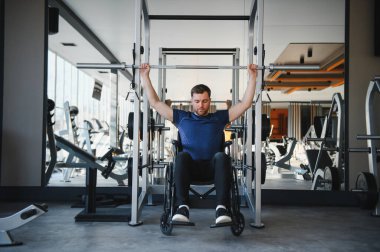 Modern spor salonunda halterle egzersiz yapan engelli bir adam dayanıklılık, dayanıklılık ve uyum sağlama yeteneğini gösteriyor.