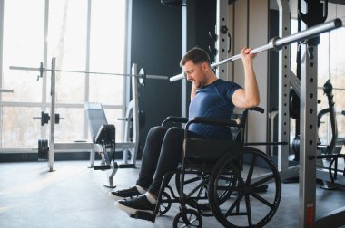 Spor salonundaki rehabilitasyonun bir parçası olarak halter kaldıran engelli kişi, güç ve kararlılığı vurguladı