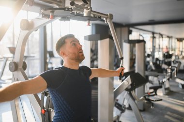 Üst vücut egzersizi için özel ekipman kullanan kararlı bir adam. Erişilebilir spor salonundaki rehabilitasyon eğitimi sırasında dayanıklılık ve güç gösteriyor.