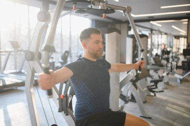 Hasta spor salonunda rehabilitasyon sırasında kendini adamış bir makine kullanarak göğüs kaslarını çalıştırıyor.