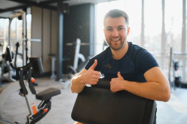 Spor salonunda rehabilitasyon egzersizleri yaparken gülümseyen adam iyileşme sürecinde azim ve ilerleme gösteriyor.