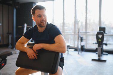 Modern bir spor salonunda rehabilitasyon sırasında dinlenen engelli bir sporcu iyileşme ve güç kazanma anının tadını çıkarıyor.